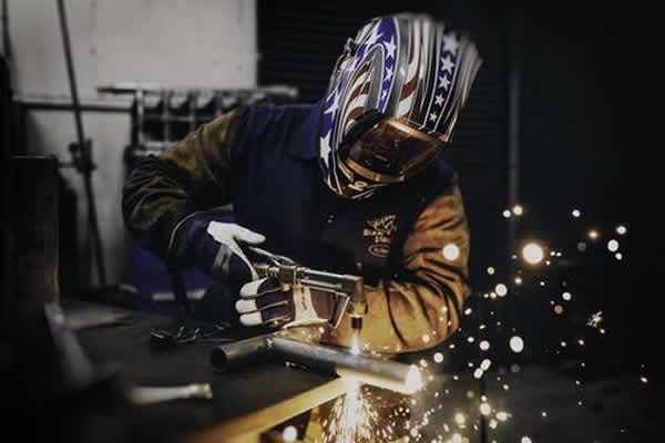 man using a cutting torch to cut a piece of metal rod