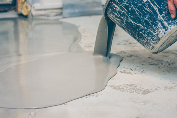 epoxy flooring being poured our of a bucket onto a floor