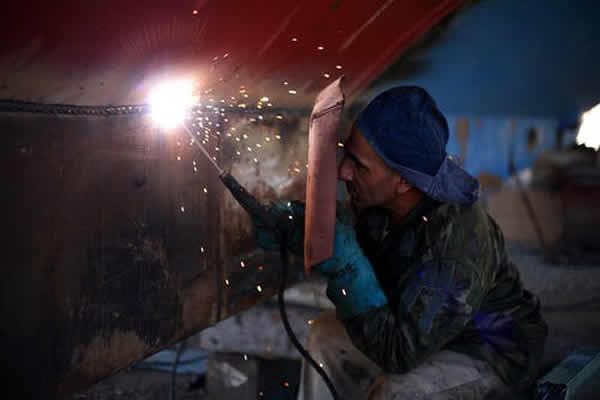 man stick welding a metal plate